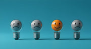 Four light bulbs, three with sad faces and one with a smiling face